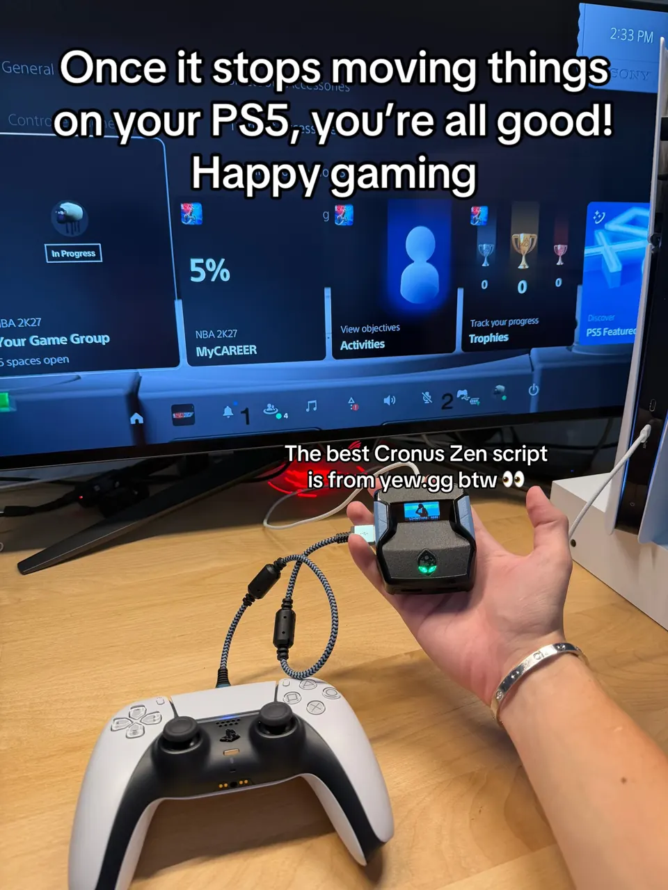 Cronus Zen with a green LED held up in front of the PS5 home screen, controller wired to it