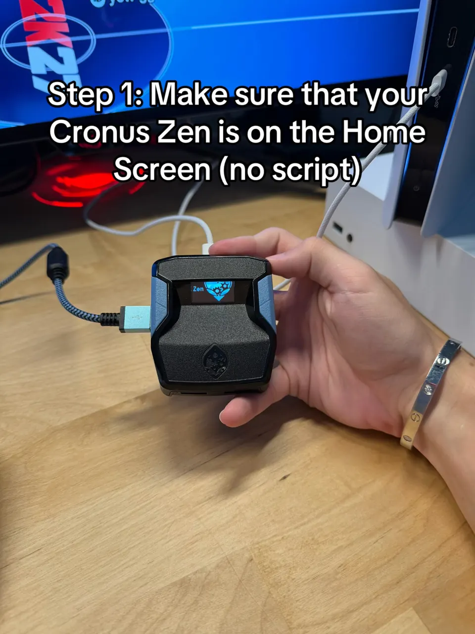 Cronus Zen held in a hand with the Cronus Zen home screen showing on the OLED
